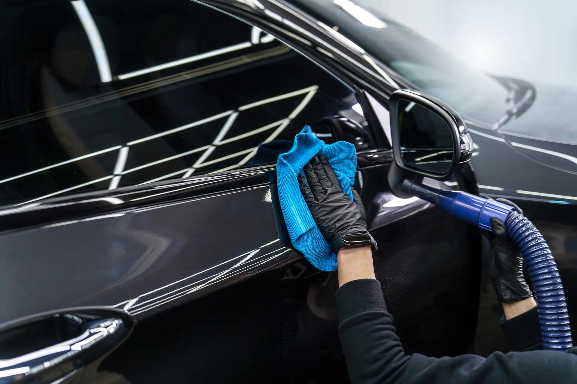 Detailer poetst een zwarte auto met microvezeldoek